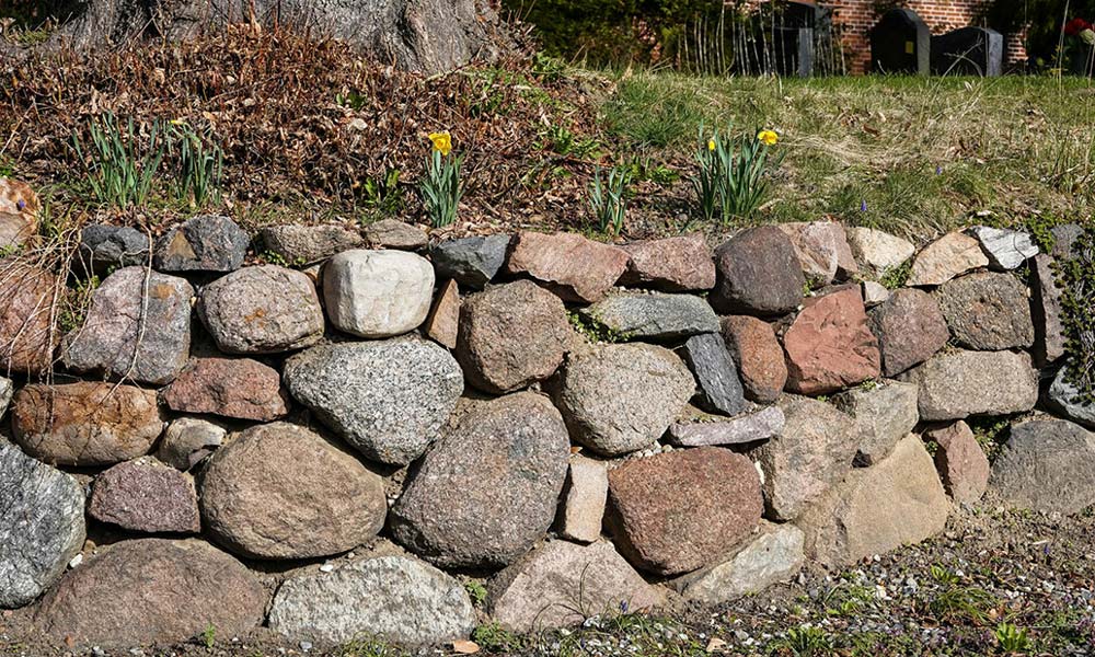 The Rounded Fieldstone Delusion That Destroys Structural Integrity in Tiered Gardens